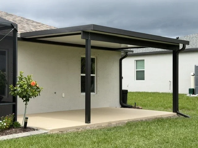 Steel pergola with retractable shade canopy over concrete patio, attached to white residential home