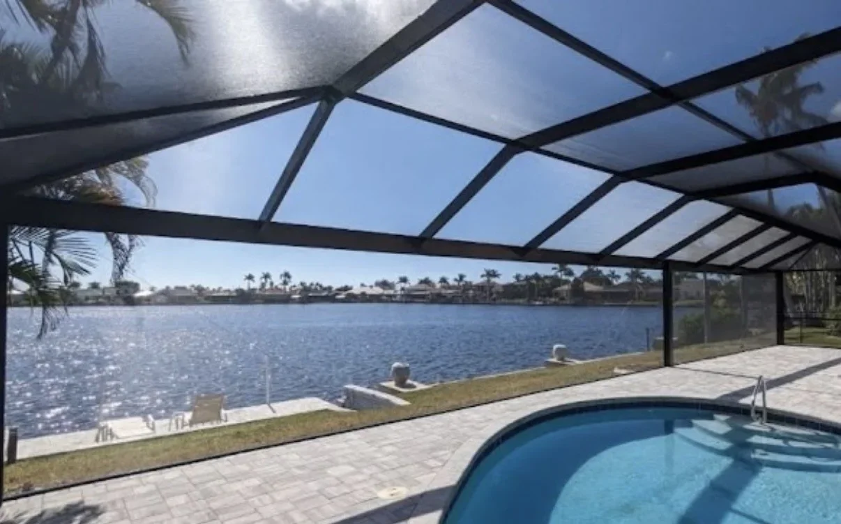 Black aluminum screen enclosure with polycarbonate roof over pool and waterfront view