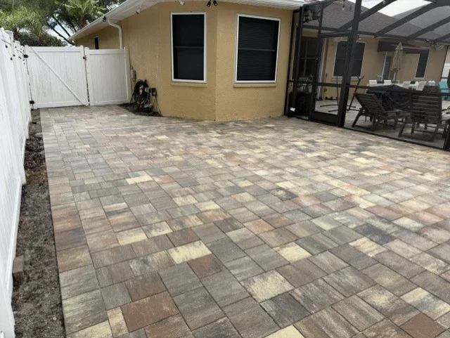 Newly installed geometric paver patio with earth-tone interlocking pavers in running bond pattern