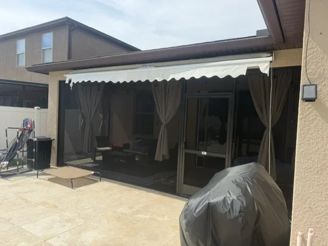 Pergola with retractable awning, sliding glass doors, motorized screens, and outdoor curtains on composite patio deck