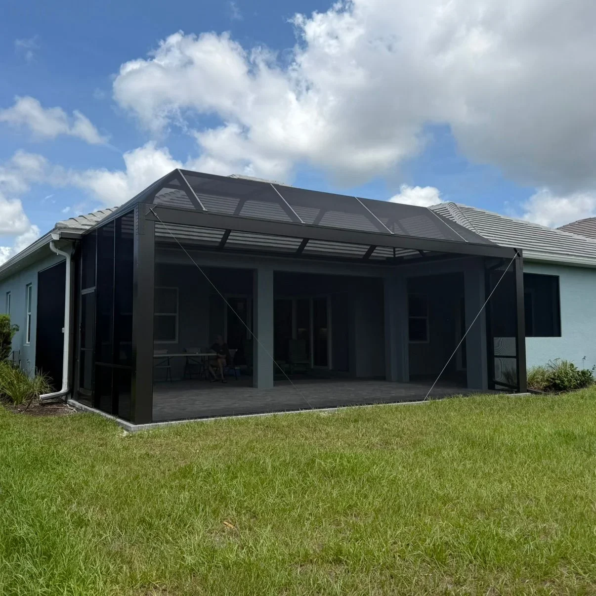 Black aluminum screen enclosure with louvered roof and full screening on residential patio