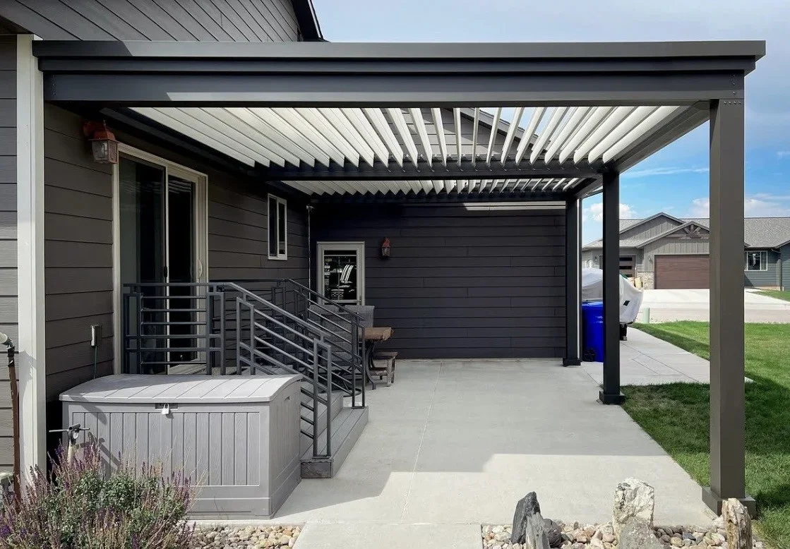 A custom wood pergola installed over a backyard patio in Apollo Beach, Florida, with open beam rafters casting shade across an outdoor seating area. The structure sits adjacent to a pool deck on a residential property typical of the Apollo Beach coastal community.